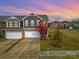 Charming two-story home with stone accents, two-car garage, and manicured front yard at sunset at 2471 Palmdale Walk Dr # 107, Fort Mill, SC 29708