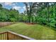 Spacious backyard featuring a lush lawn, mature trees, and a black wrought iron fence at 10221 Hanging Moss Trl, Mint Hill, NC 28227