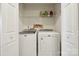 Neat laundry room area featuring a washer, dryer, and shelving at 7122 Abbotts Glen Dr, Charlotte, NC 28212