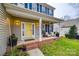 Inviting front porch with yellow door, blue shutters, and brick flooring at 1345 Shimmer Light Cir, Rock Hill, SC 29732