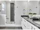 Modern bathroom featuring a glass-enclosed shower with geometric tile and white cabinets with black countertops at 3614 S Tryon St # 18, Charlotte, NC 28217