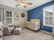 Bedroom with blue accent wall, crib, and comfortable armchair at 9507 Inverness Bay Rd, Charlotte, NC 28278