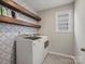 Laundry room with stylish tile backsplash, wooden shelves, and washer/dryer at 9507 Inverness Bay Rd, Charlotte, NC 28278