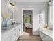 Modern bathroom leading into bedroom area, featuring double vanities, bath tub, and shower at 111 Alberta Ave, Belmont, NC 28012