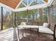 Screened porch featuring wooden floors, bench seating, and string lights with scenic backyard views at 111 Alberta Ave, Belmont, NC 28012
