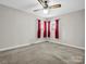 Neutral carpeted bedroom with ceiling fan and bright red curtains at 2319 Tin Mine Rd, Lincolnton, NC 28092
