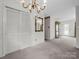 Spacious living room featuring a chandelier, closet, and bright doorway and updated carpet at 2319 Tin Mine Rd, Lincolnton, NC 28092