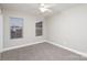 This is a bedroom with neutral walls, carpet, and a ceiling fan with two windows letting in natural light at 11005 Magna Ln, Indian Trail, NC 28079