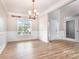 Empty formal dining room featuring chair rail, chandelier, wood-look floors, and large window at 11005 Magna Ln, Indian Trail, NC 28079