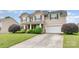 Two-story home with a stone facade, well-manicured lawn, and long concrete driveway leading to the garage at 11005 Magna Ln, Indian Trail, NC 28079