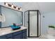 Bathroom with a stylish dark blue vanity with vessel sink and a modern glass enclosed shower at 13101 Whisper Creek Dr, Charlotte, NC 28277