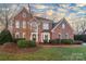 Stunning two-story red brick home with manicured landscaping and a classic design set against a bright sky at 13101 Whisper Creek Dr, Charlotte, NC 28277