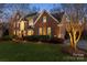 Elegant brick home featuring lush landscaping, arched windows, and warm exterior lighting at 13101 Whisper Creek Dr, Charlotte, NC 28277