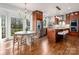 Open concept kitchen features wood floors, stainless appliances, large island, and dining area with large windows at 13101 Whisper Creek Dr, Charlotte, NC 28277