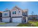 Charming two-story home featuring a light color palette, two-car garage, and manicured lawn under a clear blue sky at 165 Halite Ln, Waxhaw, NC 28173