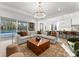 Open-concept living room with a large sectional sofa, backyard view and modern chandelier at 1015 Kendall Dr # 4, Wesley Chapel, NC 28173
