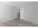 A spacious bedroom with white walls, baseboards, trim, and wood-look flooring, leads to the hallway at 440 Providence Rd, Lancaster, SC 29720