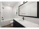 Modern bathroom with white marble tile, dark vanity, and a large mirror at 13114 Blacksmith Ct, Matthews, NC 28105