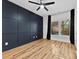 Bedroom showcasing a dark blue accent wall, hardwood floors, and a ceiling fan at 327 Coxe Ave, Charlotte, NC 28208