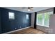 Bright bedroom with hardwood floors, blue accent wall, ceiling fan, two windows, and natural light at 327 Coxe Ave, Charlotte, NC 28208