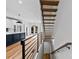 Modern floating staircase with metal railing overlooking kitchen and living area at 327 Coxe Ave, Charlotte, NC 28208