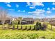 Beautiful backyard with manicured lawn, patio, outdoor kitchen, and black metal fence under a partly cloudy sky at 423 Granite Lake Ct, Denver, NC 28037