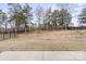 Backyard view of sloping fenced-in yard and minimal landscaping from the patio of a single-Gathering home at 4551 Selhurst Dr, Indian Land, SC 29707