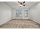 Bright bedroom with neutral carpeting, a ceiling fan, and three windows allowing natural light at 547 Old Mill Rd, Charlotte, NC 28206