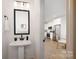 Modern powder room with pedestal sink and view of kitchen at 7420 Gwynne Cir, Charlotte, NC 28214