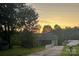 Charming single-story home with a well-maintained lawn, mature trees, and a colorful sunset in the background at 150 Windmill Ct, Harmony, NC 28634