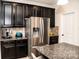 Stainless steel refrigerator in kitchen with dark cabinetry and granite counters at 3458 Canyon Live Oak Ct, Gastonia, NC 28056