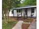 Charming exterior view of a white home with a covered porch, wooden walkway, and landscaped garden at 515 37Th Sw St, Hickory, NC 28602