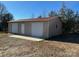 Tan metal garage with two roll-up doors and a side door at 12491 Oak Grove Rd, Stanfield, NC 28163