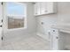 Functional laundry room featuring white cabinets, tile floors, and a bright window at 13019 Arnold Palmer Cir # 832, Lancaster, SC 29720