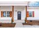 Inviting front porch with wood columns highlighting the front door and charming window shutters at 1306 Eddie St, Gastonia, NC 28054