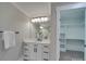 Bathroom vanity with white cabinets, modern fixtures, and closet with shelving at 1304 Pleasant Plains Rd, Matthews, NC 28105