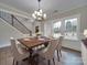 A dining room is furnished with a wood table, six upholstered chairs, and a modern chandelier above at 1304 Pleasant Plains Rd, Matthews, NC 28105