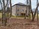 Backyard view of a brick two-story house with a fenced-in yard and a small deck surrounded by trees at 1304 Pleasant Plains Rd, Matthews, NC 28105