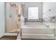 A bathroom featuring a shower-tub combo, colorful tile and a large window at 3028 Semmes Ln, Indian Trail, NC 28079