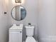 A bathroom features a white vanity and toilet with neutral walls and a round mirror at 5301 Hughes Dr, Charlotte, NC 28213