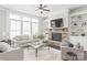 Bright living room featuring a stone fireplace, built-in bookshelves, large windows, and neutral furniture at 1209 Cedar Park Dr, Pineville, NC 28134