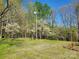 Backyard featuring lush green grass, mature trees and a sunny blue sky at 16480 Indian Mound Rd, Norwood, NC 28128