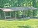 Carport with a corrugated roof and beams surrounded by lush green grass and trees at 16480 Indian Mound Rd, Norwood, NC 28128