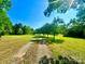 Long driveway leading through a sunny, grassy field lined with mature trees at 16480 Indian Mound Rd, Norwood, NC 28128