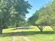 A long driveway leads to a beautiful property, framed by mature trees and green grass on either side at 16480 Indian Mound Rd, Norwood, NC 28128