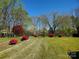 The front yard showcases vibrant landscaping with flowering shrubs, green grass, and mature trees at 16480 Indian Mound Rd, Norwood, NC 28128
