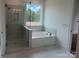 Luxurious bathroom with a separate glass-enclosed shower and a soaking tub under a large window at 320 Triple Ponds Ct, Clover, SC 29710