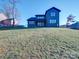 Back of the home featuring dark siding, black trim, and a manicured yard, blending modern design with natural surroundings at 8039 Mcconnell Rd, Denver, NC 28037