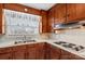 Retro kitchen features wood cabinets, four-burner stovetop, and a double sink at 129 Ann St, Salisbury, NC 28146