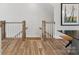 Staircase landing featuring hardwood floors, light wood posts, and white wood railings at 8005 Elevate Ct, Charlotte, NC 28205